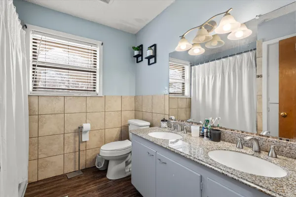 a bathroom with a granite countertop sink a toilet and a large mirror