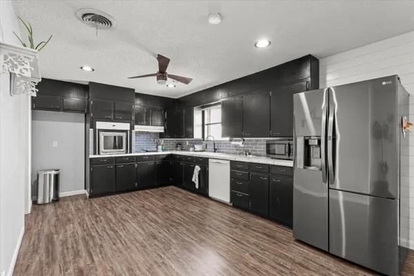 a kitchen with stainless steel appliances kitchen island granite countertop a refrigerator a sink dishwasher a kitchen island with wooden cabinets and floor