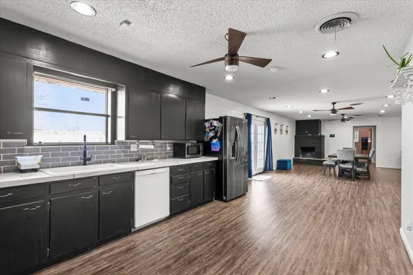 a large kitchen with stainless steel appliances a large counter top a sink a stove and a refrigerator