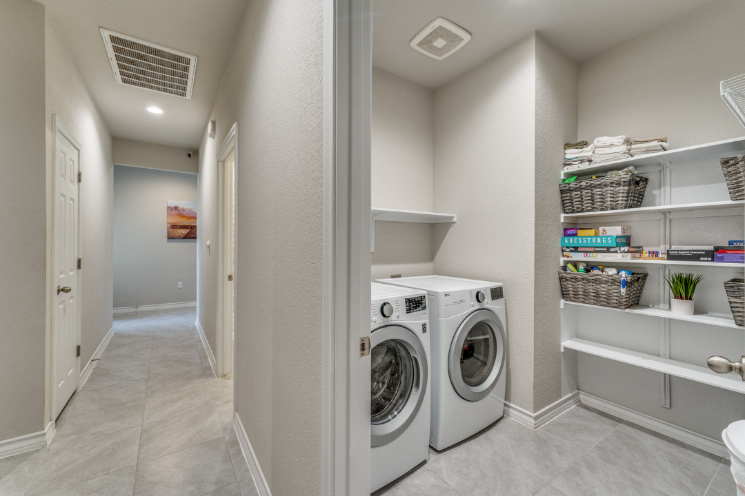5921 Lehman Way Austin, TX 78747 - Photo 18 of 25 Functional laundry room equipped with contemporary appliances and ample storage shelves.