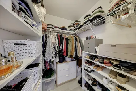 a view of walk in closet with clothes and shoes