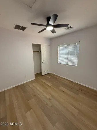 an empty room with wooden floor ceiling fan and windows