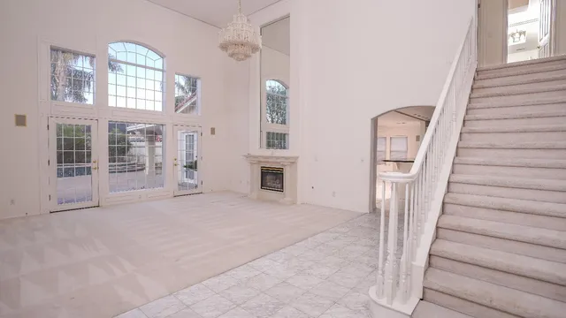 a view of an empty room with stairs and a window