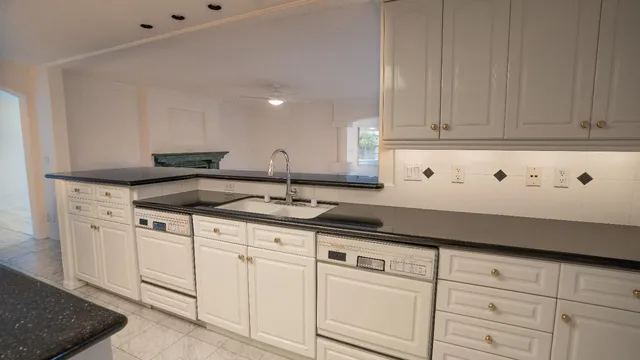 a kitchen with granite countertop white cabinets and a sink