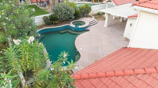 an aerial view of a house with outdoor space and trees all around