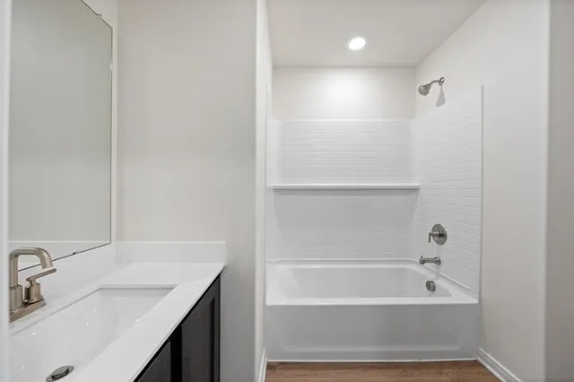 a bathroom with a tub sink vanity and mirror