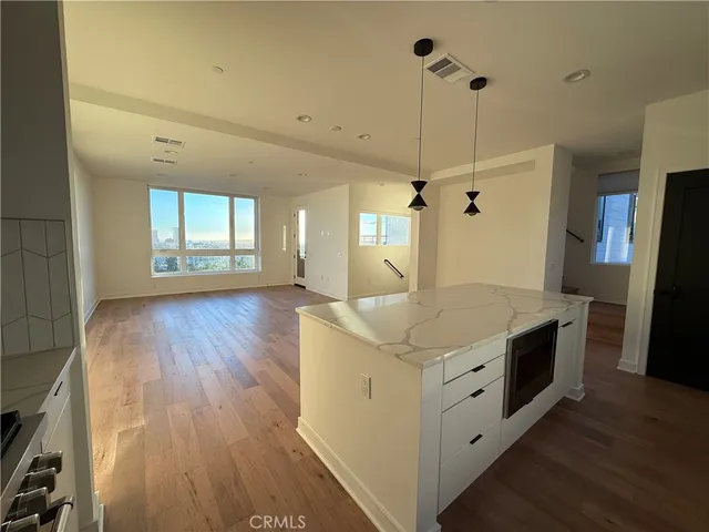 a kitchen with stainless steel appliances granite countertop a sink a counter space and wooden floor