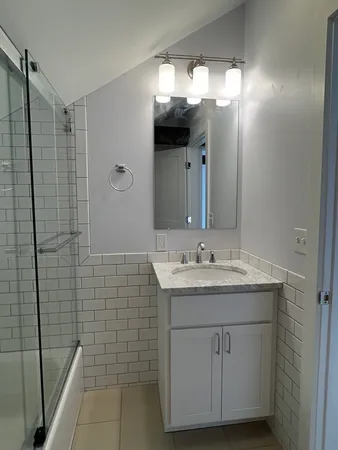 a bathroom with a granite countertop sink a toilet a mirror and shower
