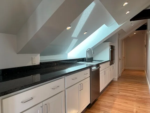 a large white kitchen with stainless steel appliances granite countertop a sink and a stove