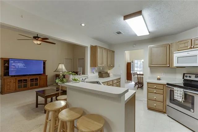 a living room with furniture a rug kitchen view and a window