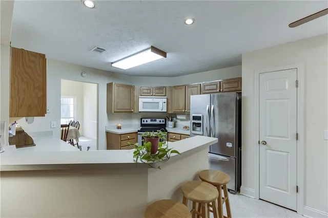a kitchen with sink refrigerator and chairs