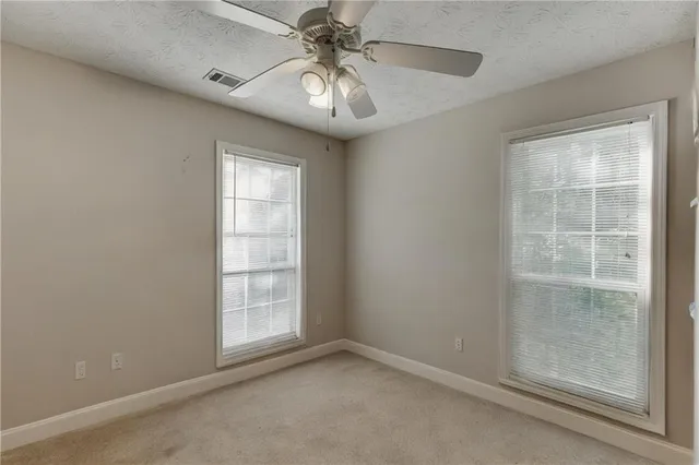 an empty room with windows and fan