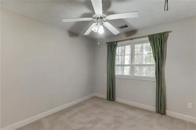 an empty room with a ceiling fan and windows