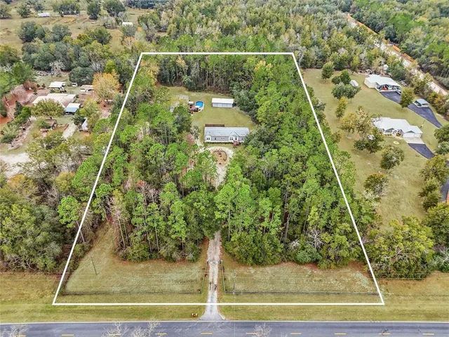 an aerial view of a house with pool garden and a yard