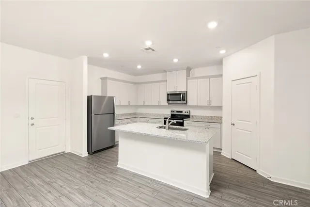a kitchen with a refrigerator a white cabinets and wooden floor