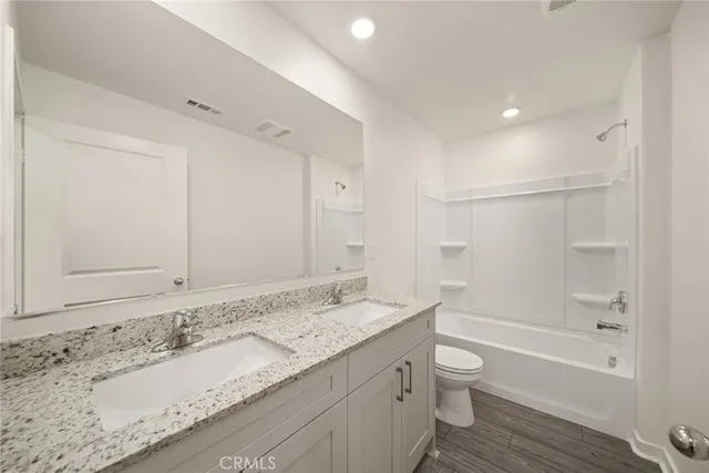 a bathroom with a granite countertop sink a toilet and bathtub