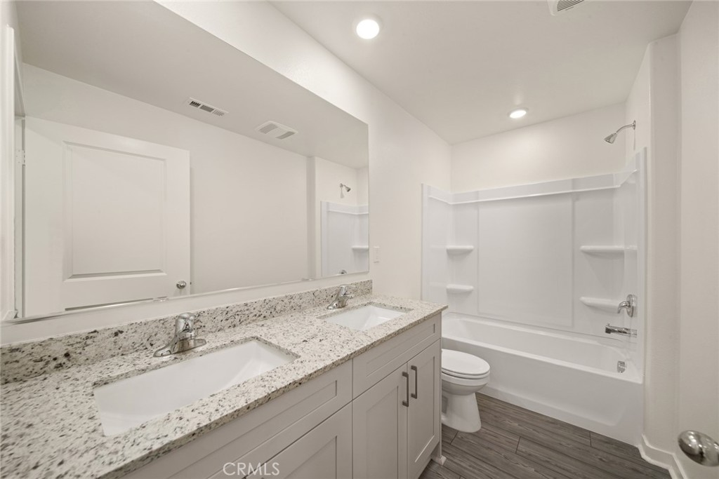 42499 Aruba Court Indio, CA 92201 - Photo 9 of 22 a bathroom with a granite countertop sink a toilet and bathtub