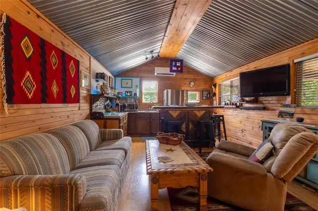 a living room with furniture a flat screen tv and floor to ceiling window