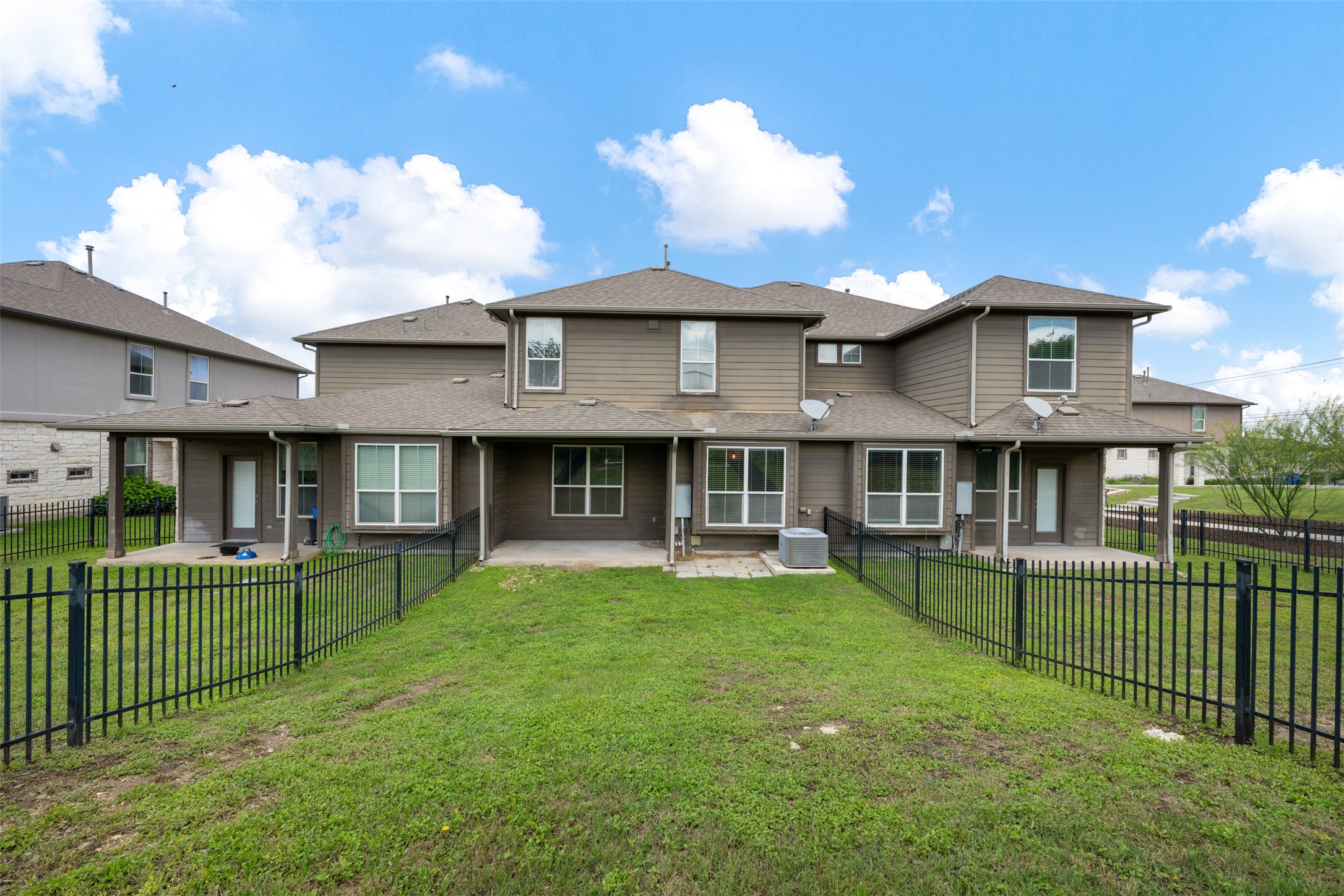 211 Parable Cove Pflugerville, TX 78660 - Photo 38 of 40 Expansive backyard featuring a manicured lawn, black metal fencing, and multiple covered patio areas