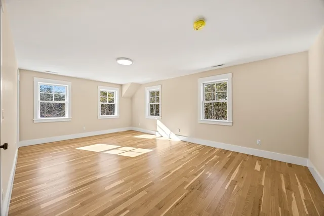 a view of an empty room with window and wooden floor