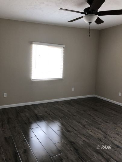 1352 Sydnor Avenue Ridgecrest, CA 93555 - Photo 14 of 26 an empty room with wooden floor fan and windows