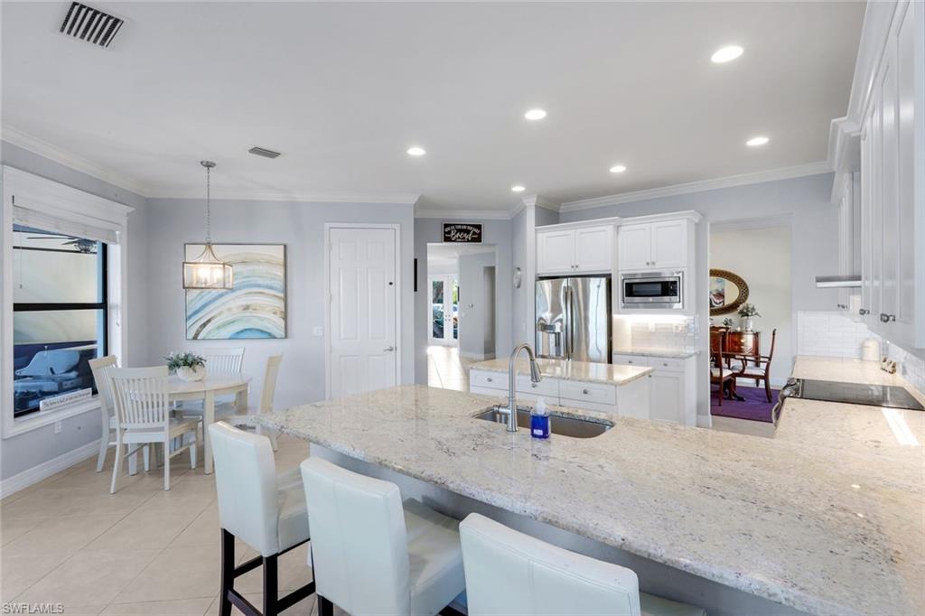 2735 Cinnamon Bay Circle Naples, FL 34119 - Photo 8 of 50 a kitchen with stainless steel appliances kitchen island granite countertop a sink and cabinets