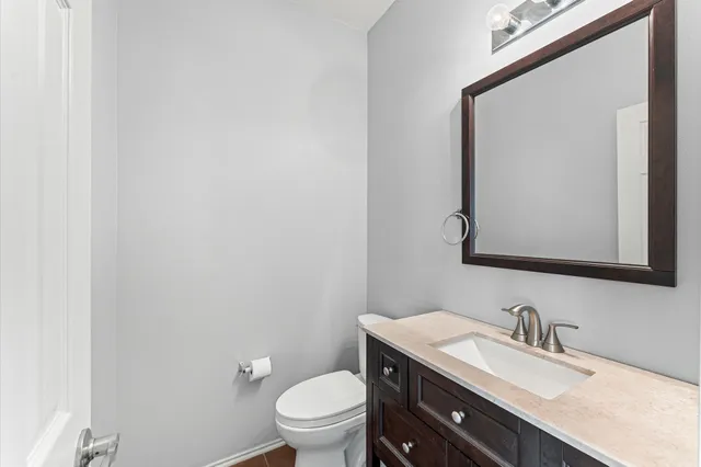 a bathroom with a granite countertop toilet sink mirror and vanity