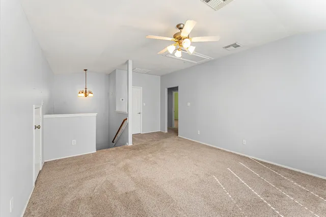 a view of an empty room with a chandelier fan
