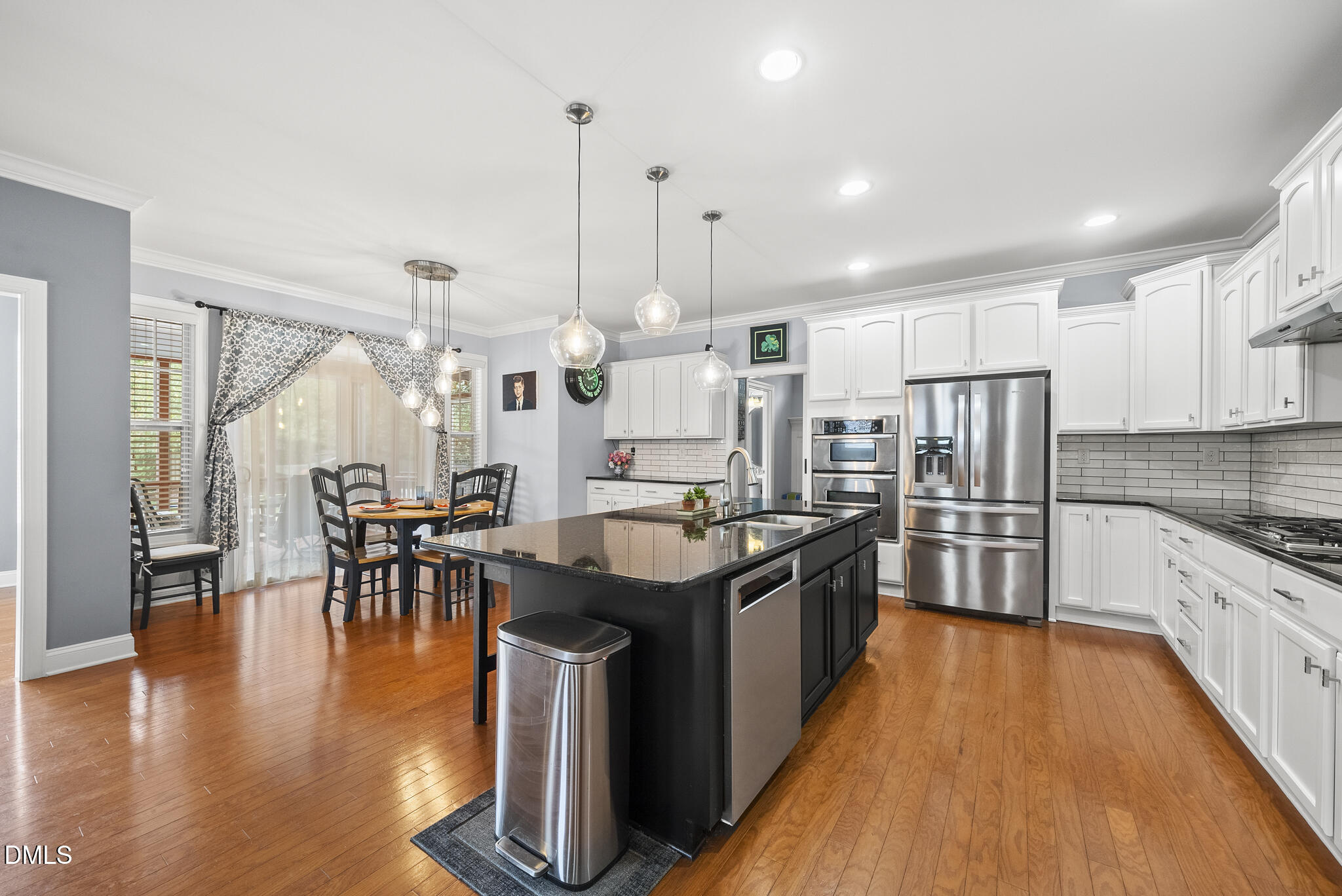 424 Powers Ferry Road Cary, NC 27519 - Photo 17 of 88 a kitchen with stainless steel appliances granite countertop a stove top oven a sink a dining table and chairs with wooden floor