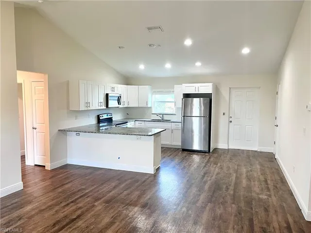 a kitchen with wooden floors white cabinets and stainless steel appliances