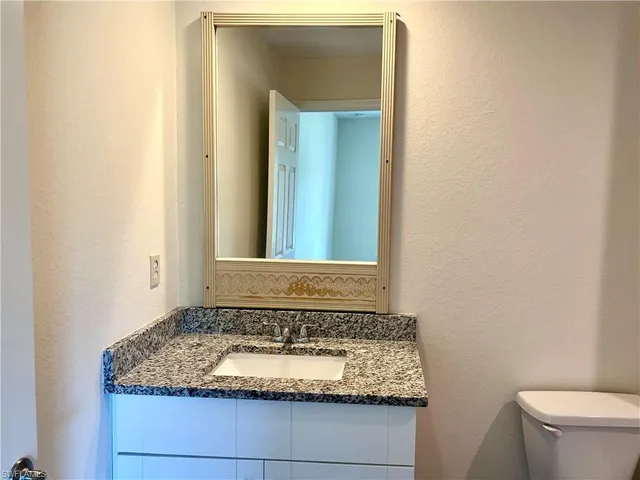 a bathroom with a granite countertop sink and a mirror