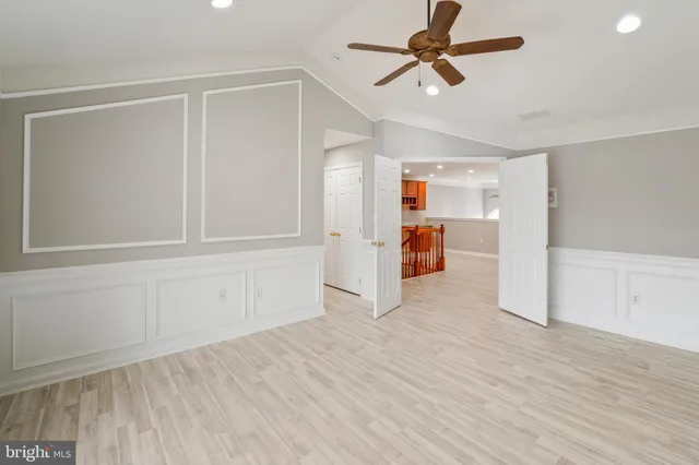 a view of empty room with wooden floor and ceiling fan