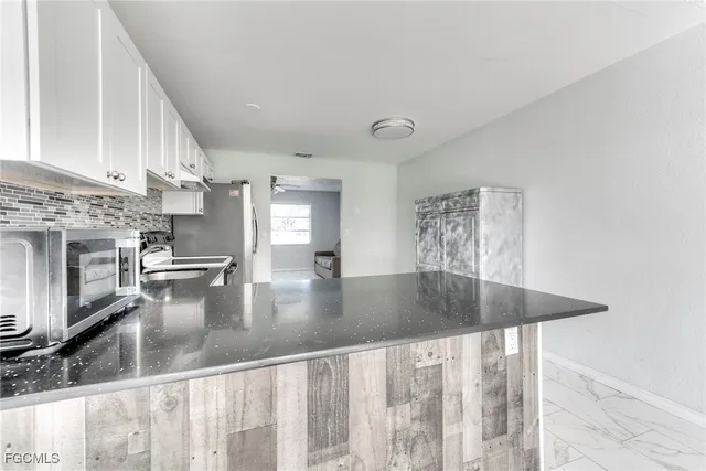 a view of a livingroom with a chandelier fan and windows