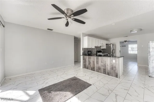 a view of kitchen and empty room with wooden floor