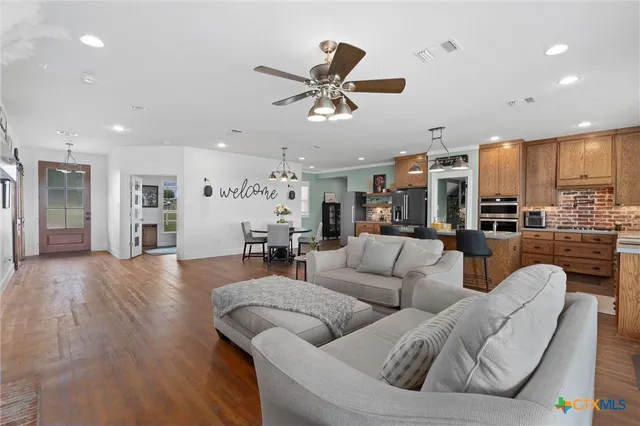 a living room with furniture kitchen view and a chandelier