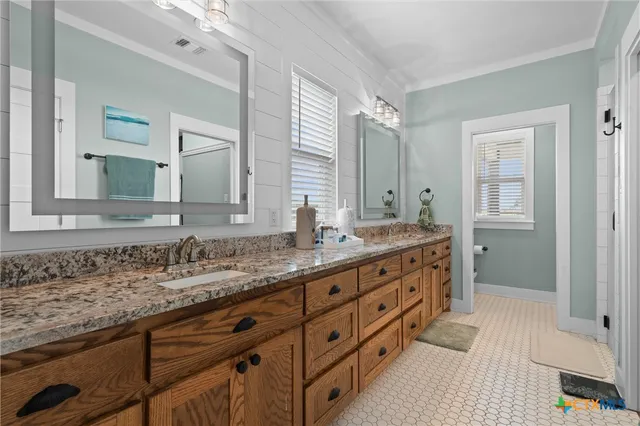 a bathroom with a granite countertop double vanity sink and mirror