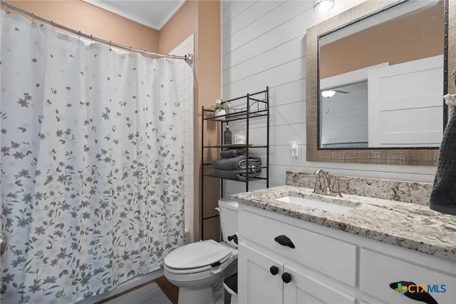 a bathroom with a granite countertop toilet sink mirror and shower