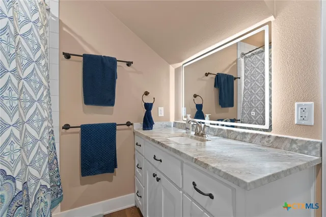 a bathroom with a granite countertop sink and a mirror