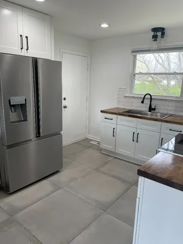 a kitchen with stainless steel appliances a sink a stove a refrigerator a counter top oven and a window