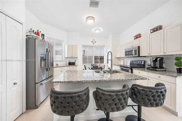a kitchen with stainless steel appliances granite countertop a sink refrigerator and cabinets