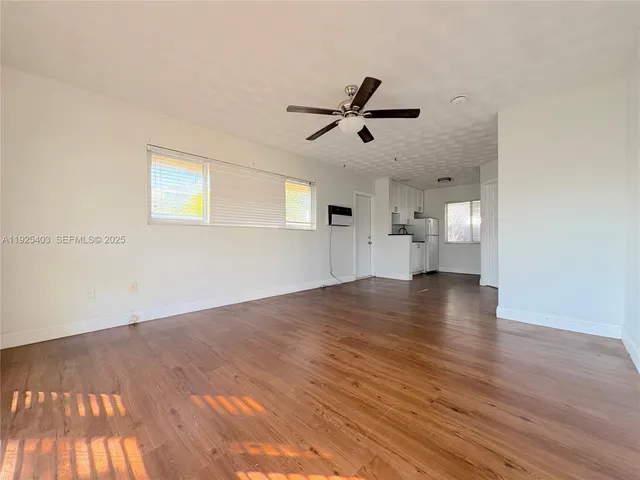 a view of empty room with wooden floor and ceiling fan