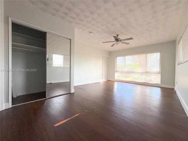 an empty room with wooden floor chandelier and windows