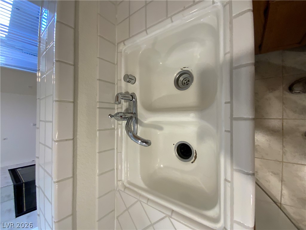 7400 West Flamingo Road, Unit 1039 Las Vegas, NV 89147 - Photo 18 of 40 Double sink with tile backsplash, blending practicality with a neat aesthetic.