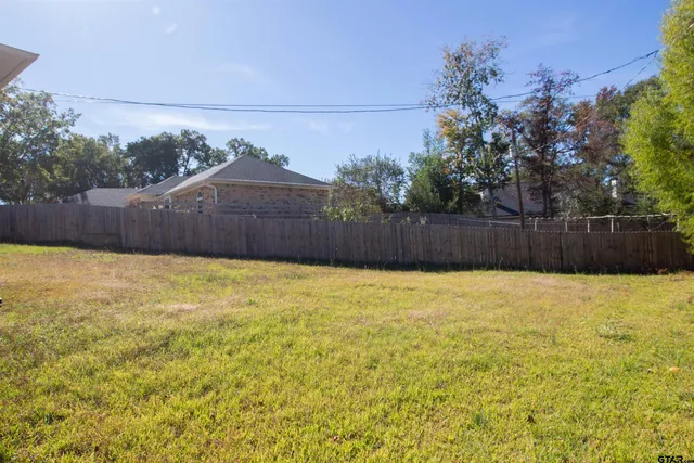 a backyard of a house with wooden fence and large trees