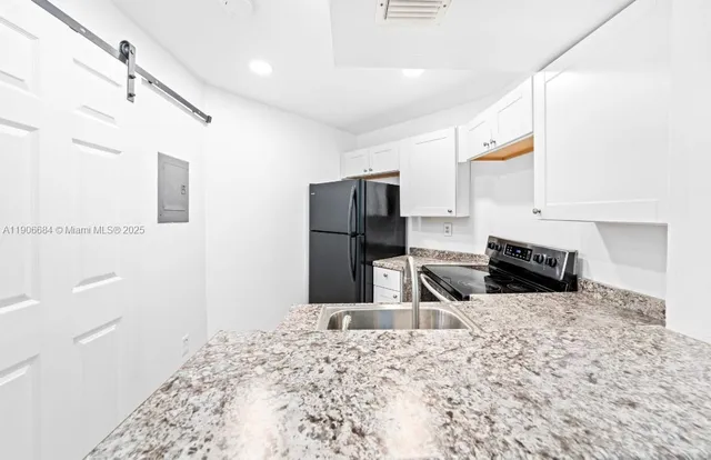 a kitchen with granite countertop a refrigerator and a sink