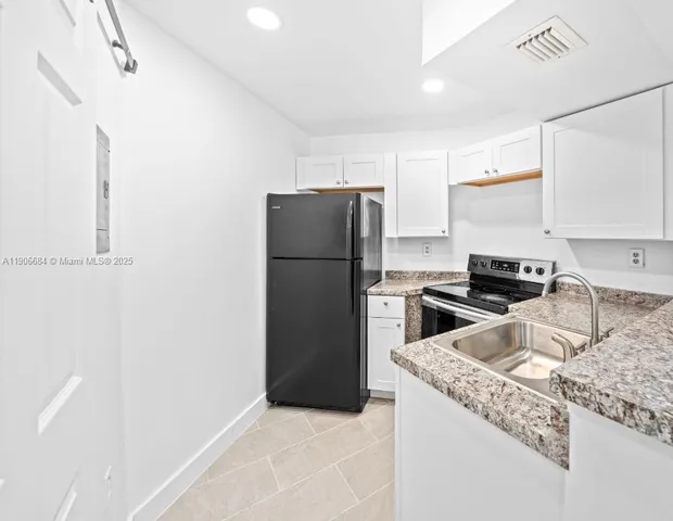 a kitchen with granite countertop a refrigerator and a sink