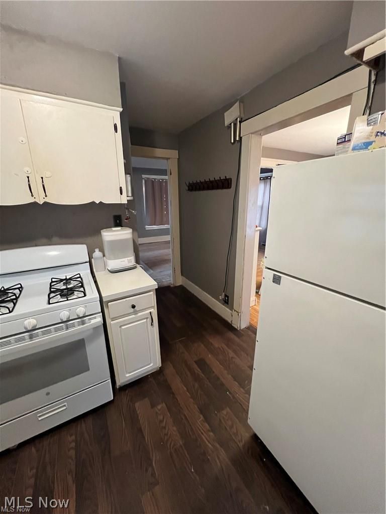 1911 Youngstown Road Southeast Warren, OH 44484 - Photo 6 of 17 Kitchen featuring white fridge, range, light countertops, white cabinetry, and dark wood-style flooring