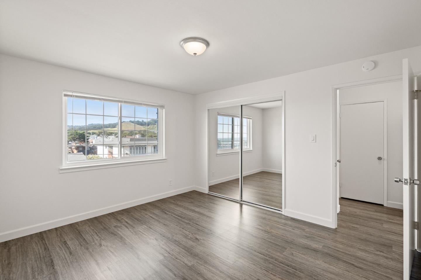 127 Hilton Way Pacifica, CA 94044 - Photo 16 of 18 an empty room with wooden floor and windows