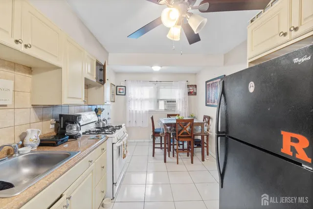 a kitchen with stainless steel appliances granite countertop a refrigerator a sink a stove and white cabinets