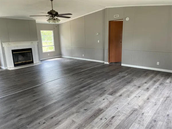 an empty room with wooden floor fireplace and windows